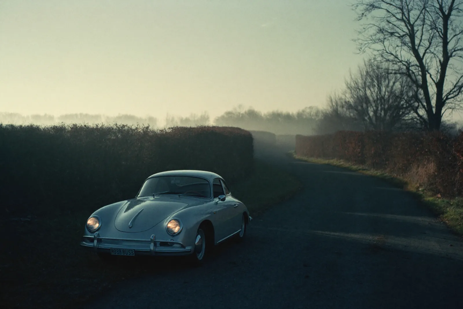 AI-generated illustration: a silver Porsche 356 coupe on an empty alpine road in October morning fog.